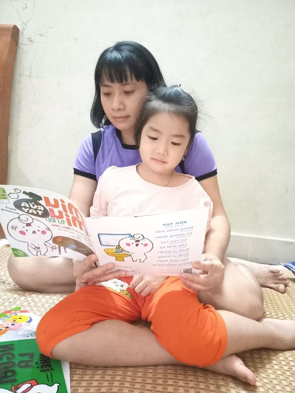 Hình ảnh mẹ đọc sách cho bé nghe khi ở nhà và mẹ hướng dẫn bé xem sách.