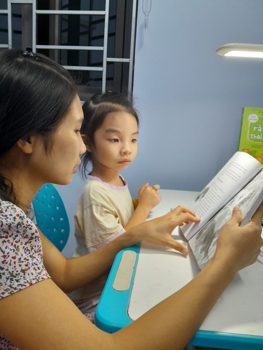 Hình ảnh mẹ đọc sách cho bé nghe khi ở nhà và mẹ hướng dẫn bé xem sách.